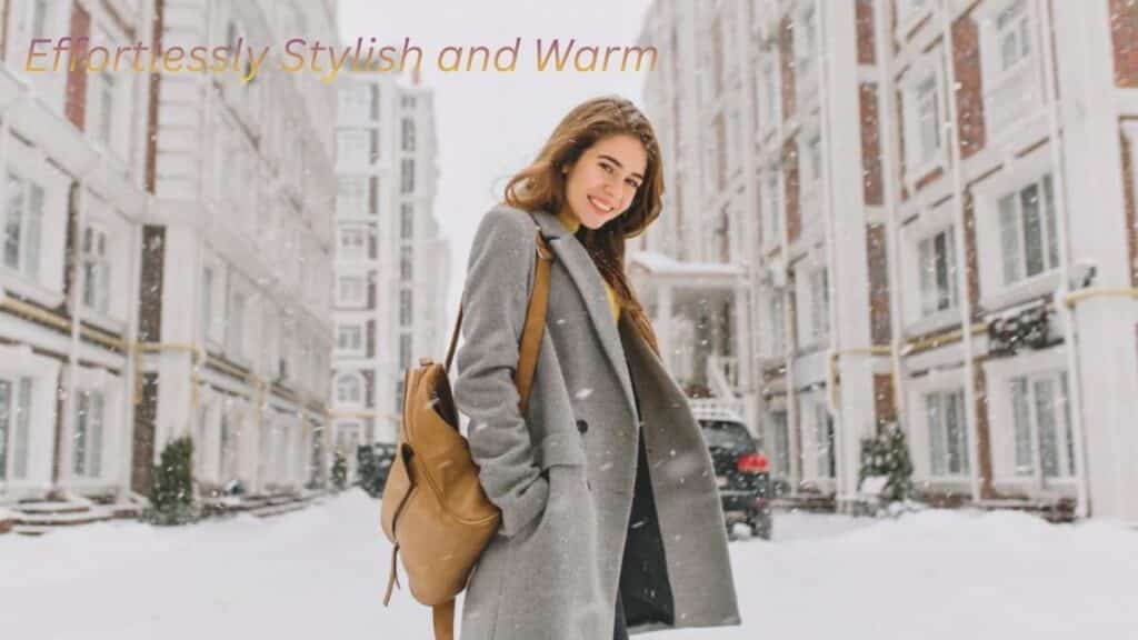 "Woman in a stylish gray coat walking in the snow, looking effortlessly warm and fashionable."