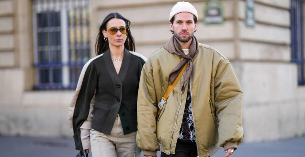 "A fashion-forward streetwear scene featuring a model in an oversized wool coat layered with a chunky knit scarf, embodying bold comfort for winter 2025."