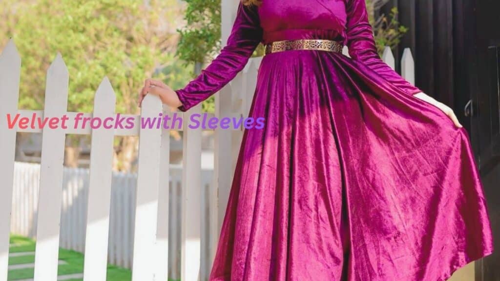 "Elegant woman in a purple velvet frock with long sleeves, posing by a white fence."