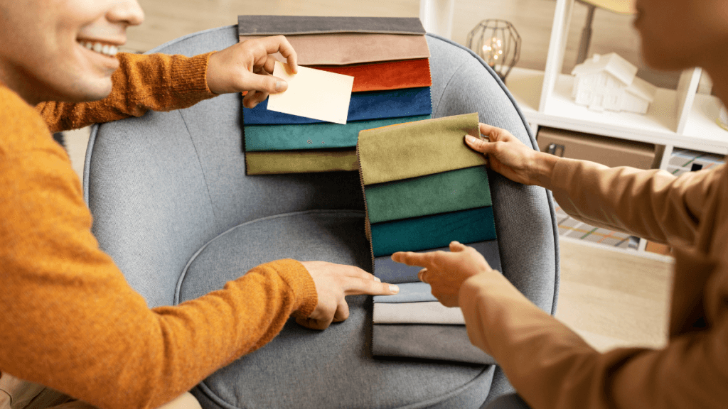 People selecting fabric swatches in various colors while sitting by a chair during a design consultation.