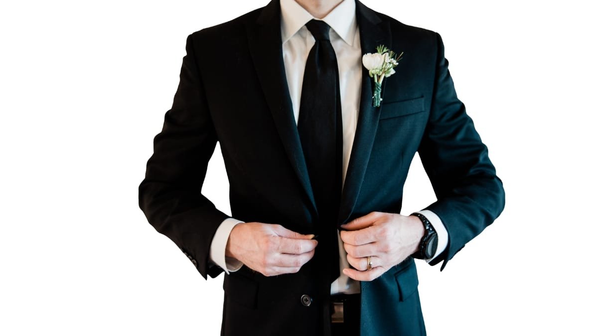 Dressy suits for wedding: Man adjusting his tie in a black suit