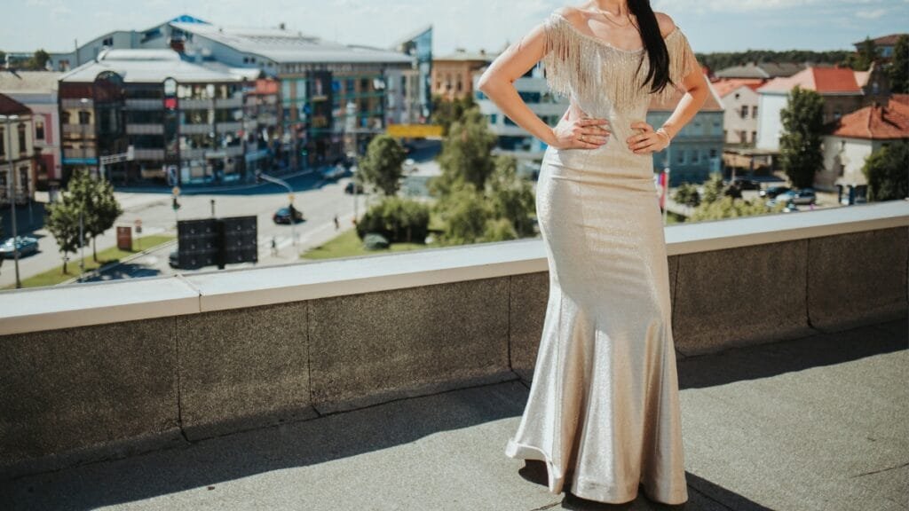 Bride in a flowing white gown, standing on a beach at sunset