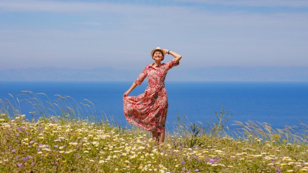 Woman wearing a floral midi sundress in a field with a scenic ocean view.
