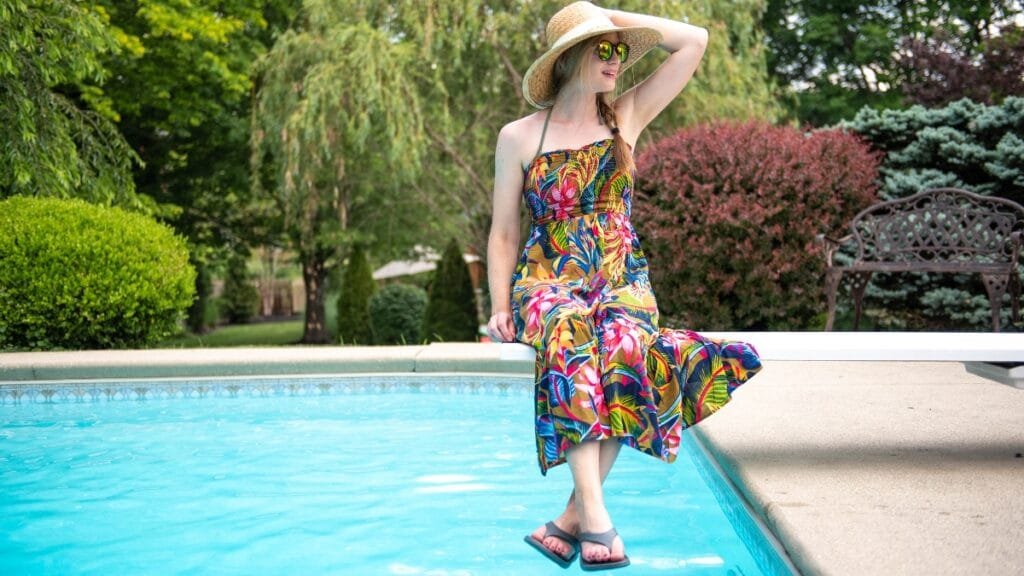 Woman wearing a tropical floral midi sundress by the poolside.