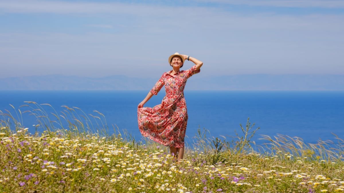 Woman wearing a floral midi sundress in a field with a scenic ocean view.