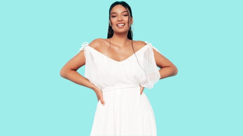 Plus size woman wearing an off-shoulder white dress with tie straps and a relaxed, flowing silhouette.