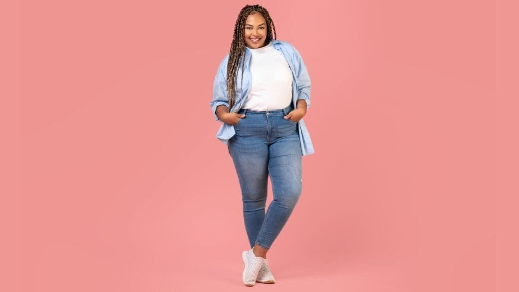 A plus-size woman wearing a light blue shirt and denim jeans, offering a trendy and comfortable outfit idea for short fat ladies
