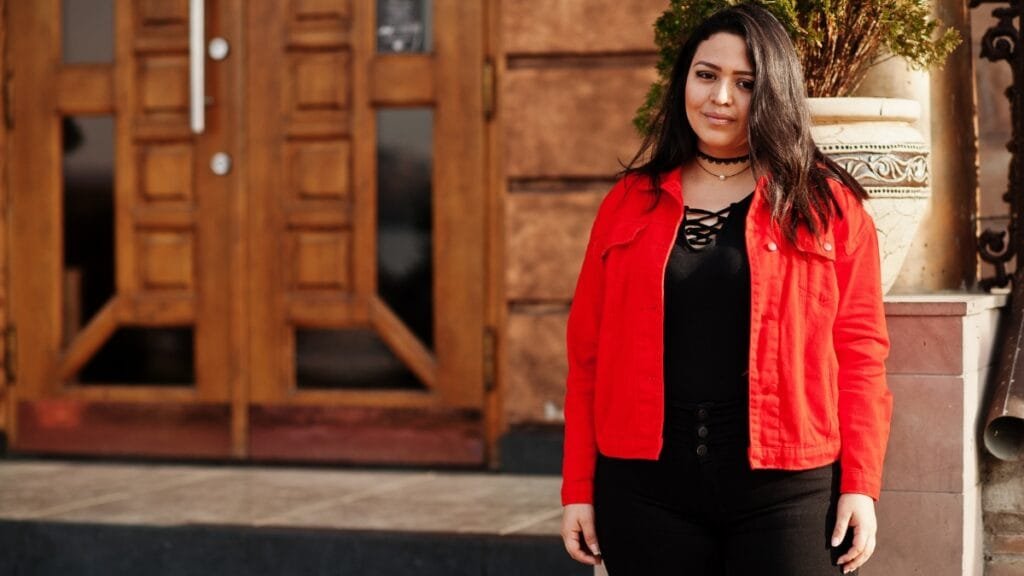 A woman in a red jacket and black jeans, a stylish outfit choice for short fat ladies looking to make a bold statement