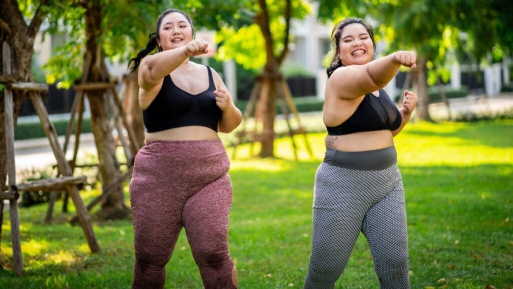 Plus size women in vibrant activewear, wearing colorful track pants while exercising outdoors.