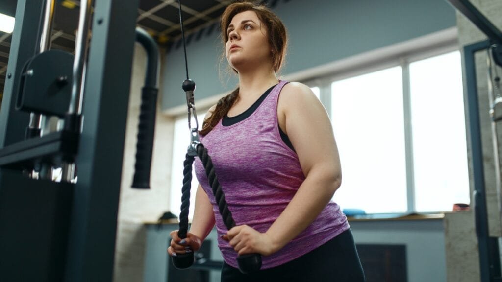 Plus size woman working out with a purple workout tank top