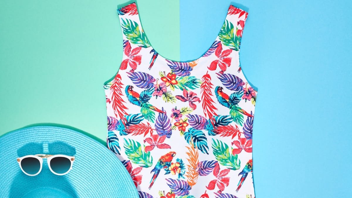 Women’s floral swim tankini displayed on a blue background with sunglasses