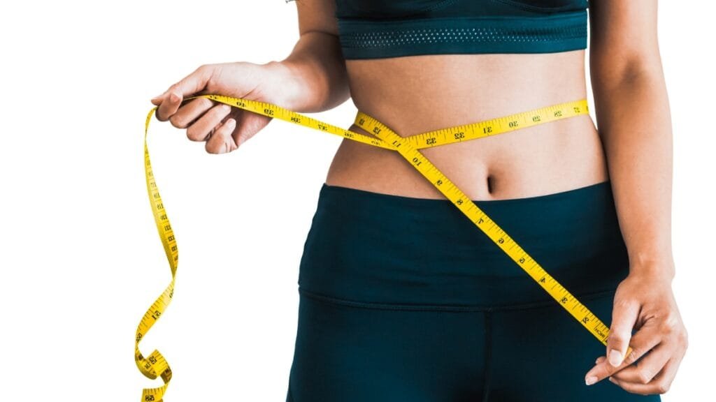 Close-up of a woman measuring her waist with a yellow measuring tape
