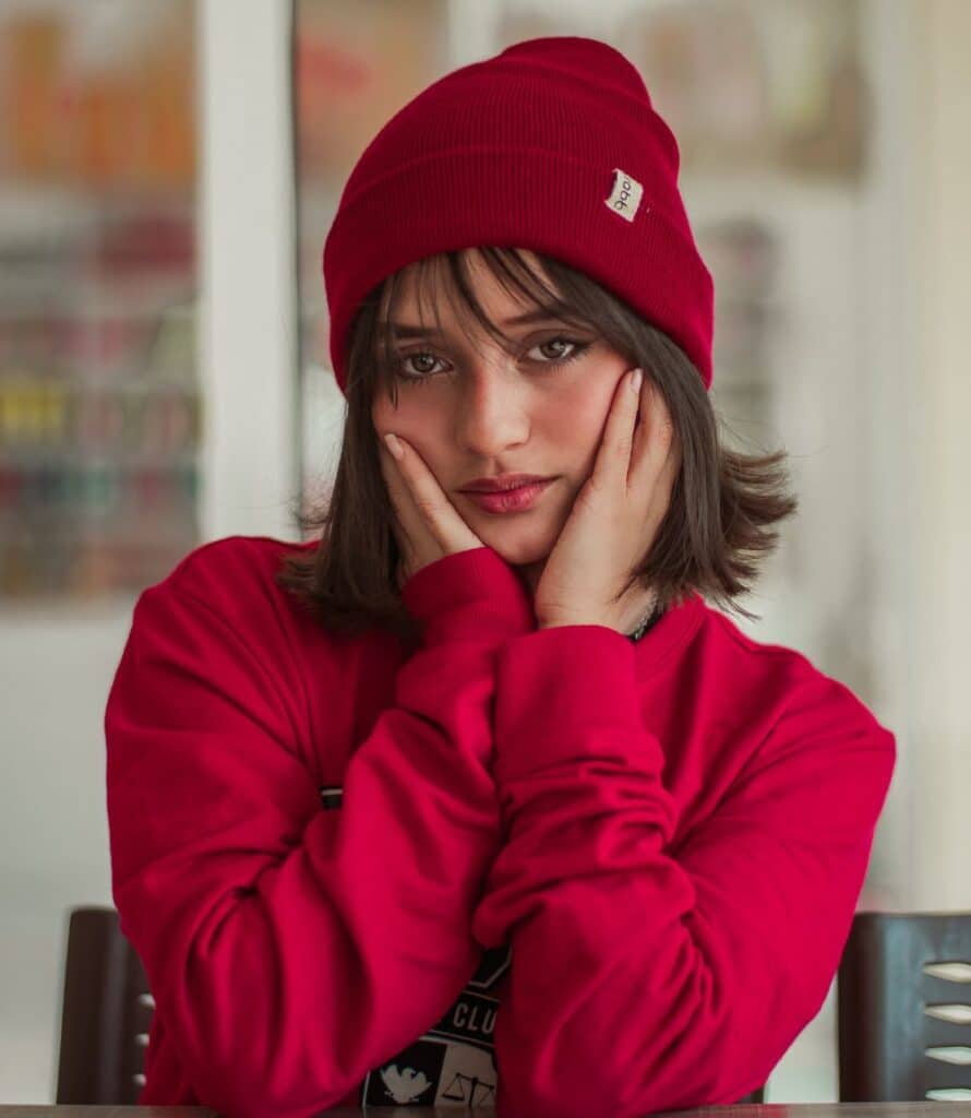 A factory floor showing a beanie embroidery machine stitching a logo onto a black beanie.