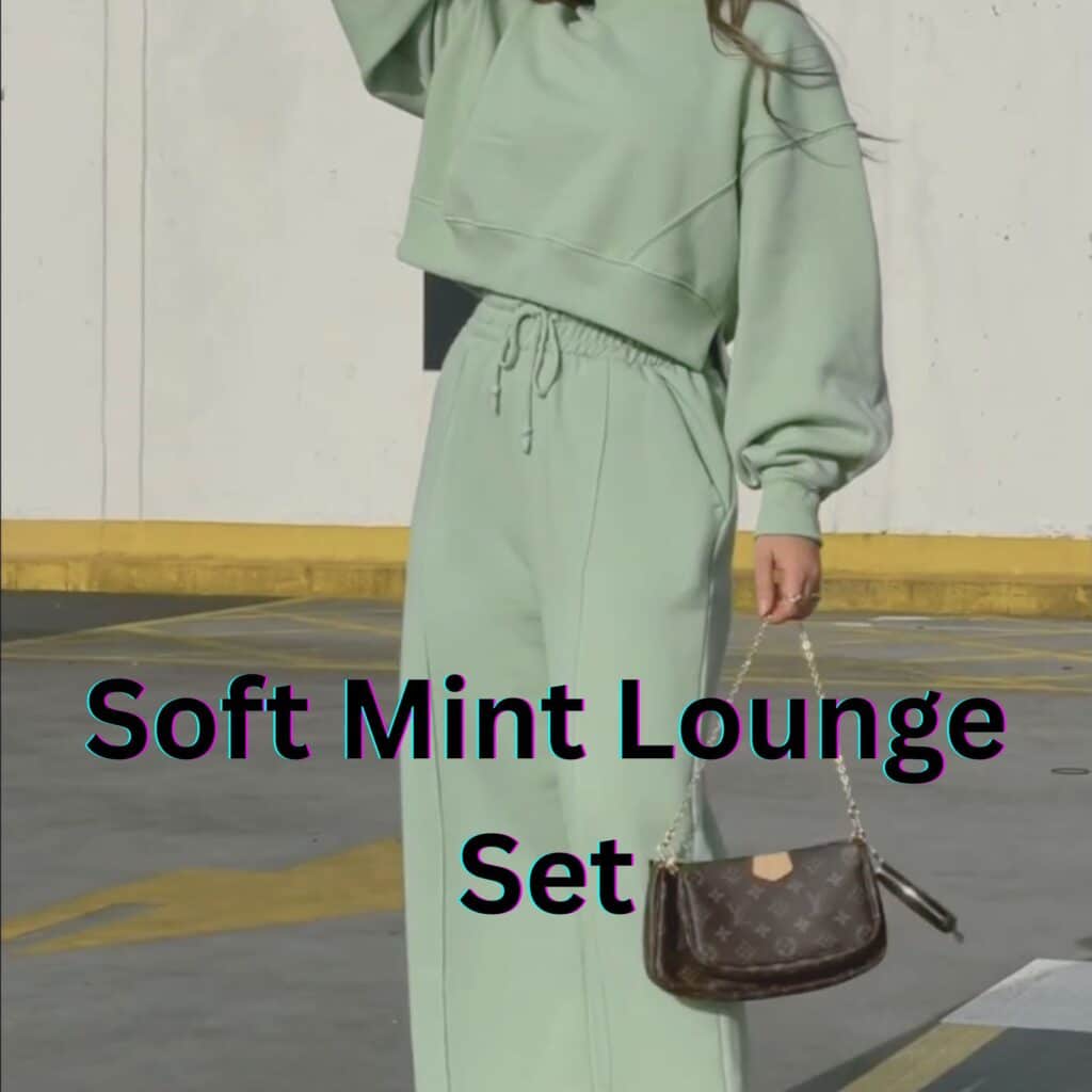 Woman wearing a soft mint green matching lounge set with a cropped sweatshirt and drawstring wide-leg pants, holding a small brown Louis Vuitton handbag with a chain strap, standing in a parking lot.