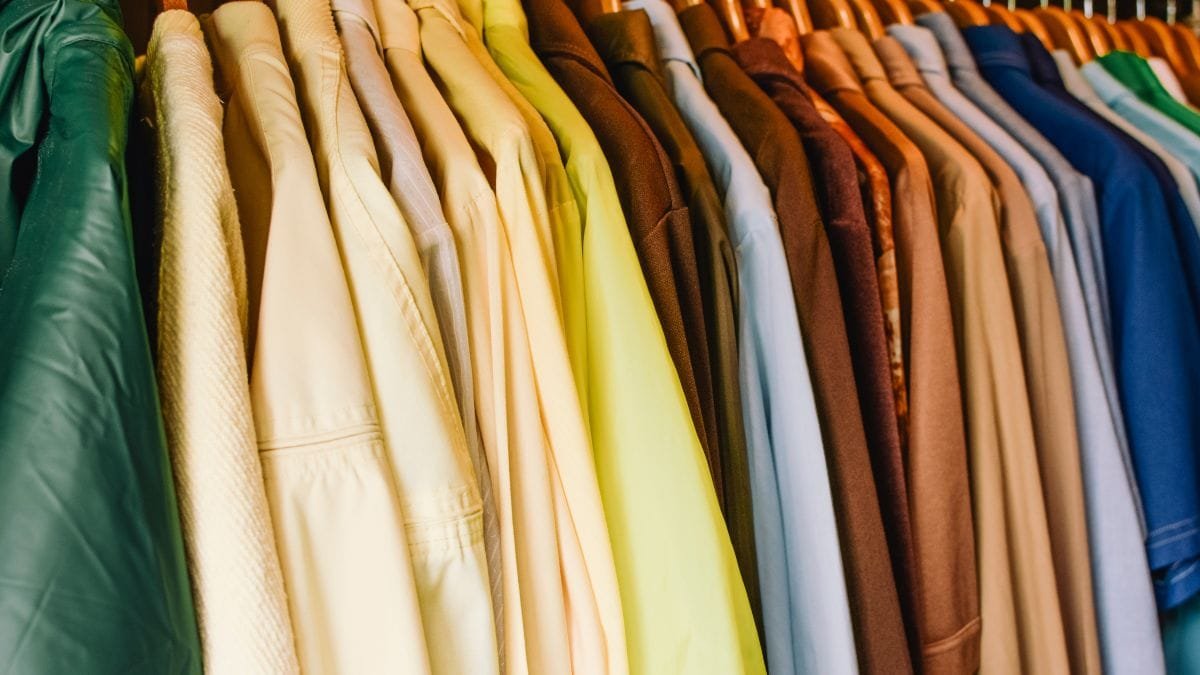 A collection of shirts in various colors hanging neatly in a wardrobe.