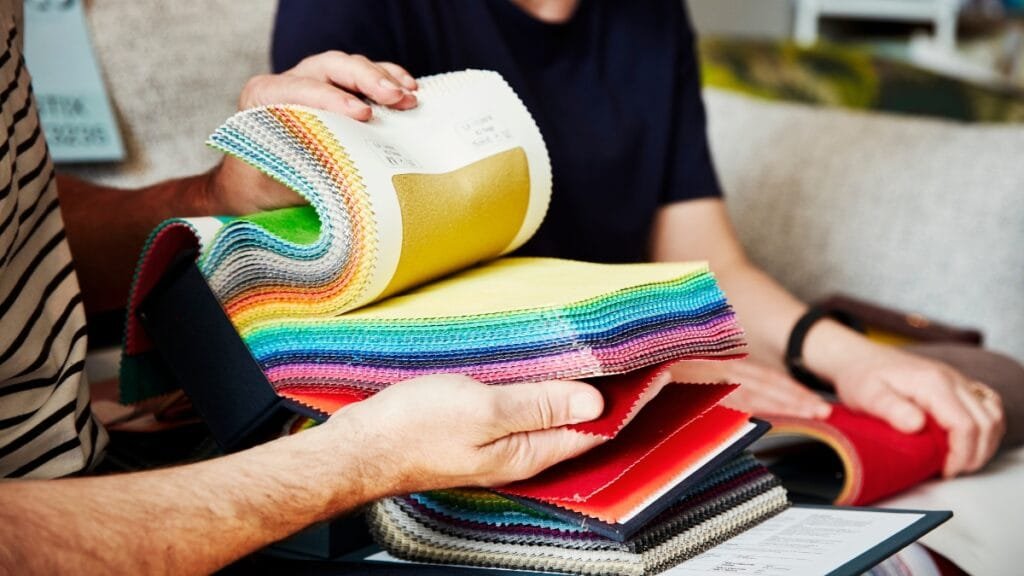 A close-up of fabric swatches being flipped through, displaying a variety of fabric textile products in different colors