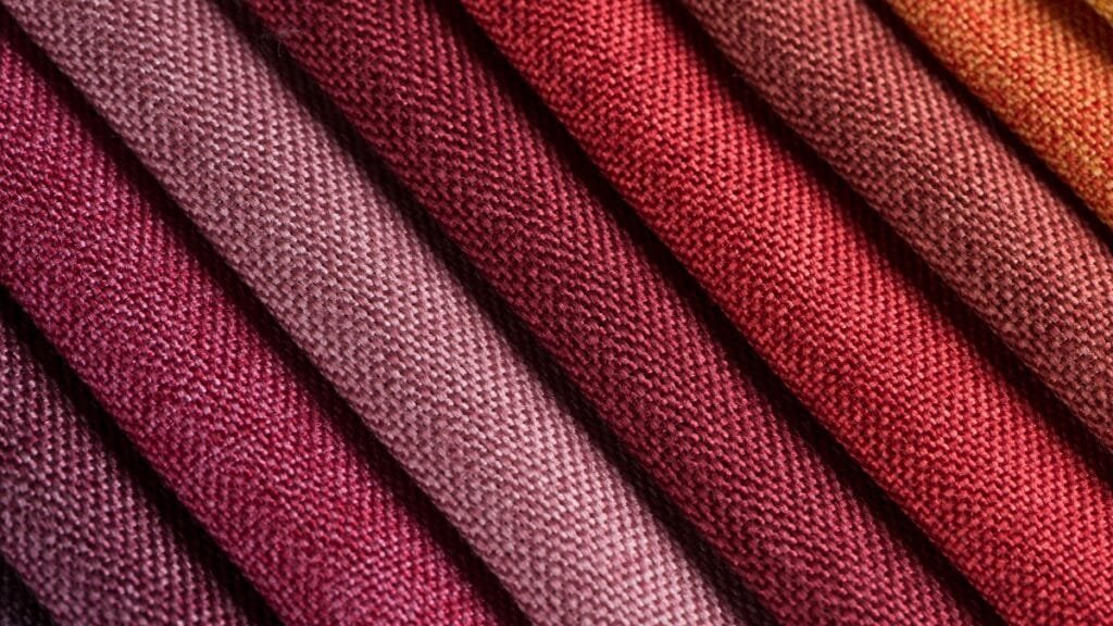 A gradient of rich red to pink fade-resistant fabric rolls