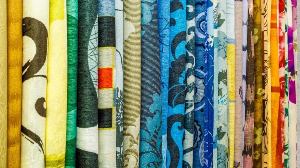 A collection of fabric rolls with floral patterns in a range of colors, showcasing iconic fabric designs