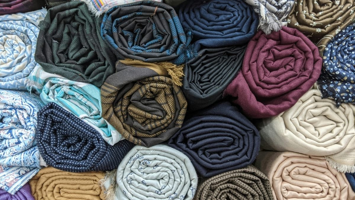 Different types of sewing machine fabric rolled up in various colors and patterns