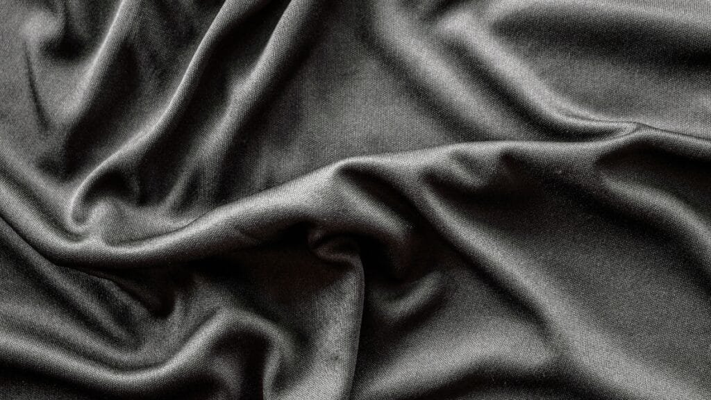 Black two-way stretch fabric with smooth folds, highlighting its stretchability