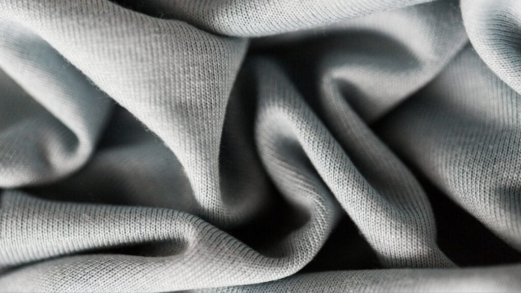 Light grey two-way stretch fabric close-up showing its smooth texture and flexibility