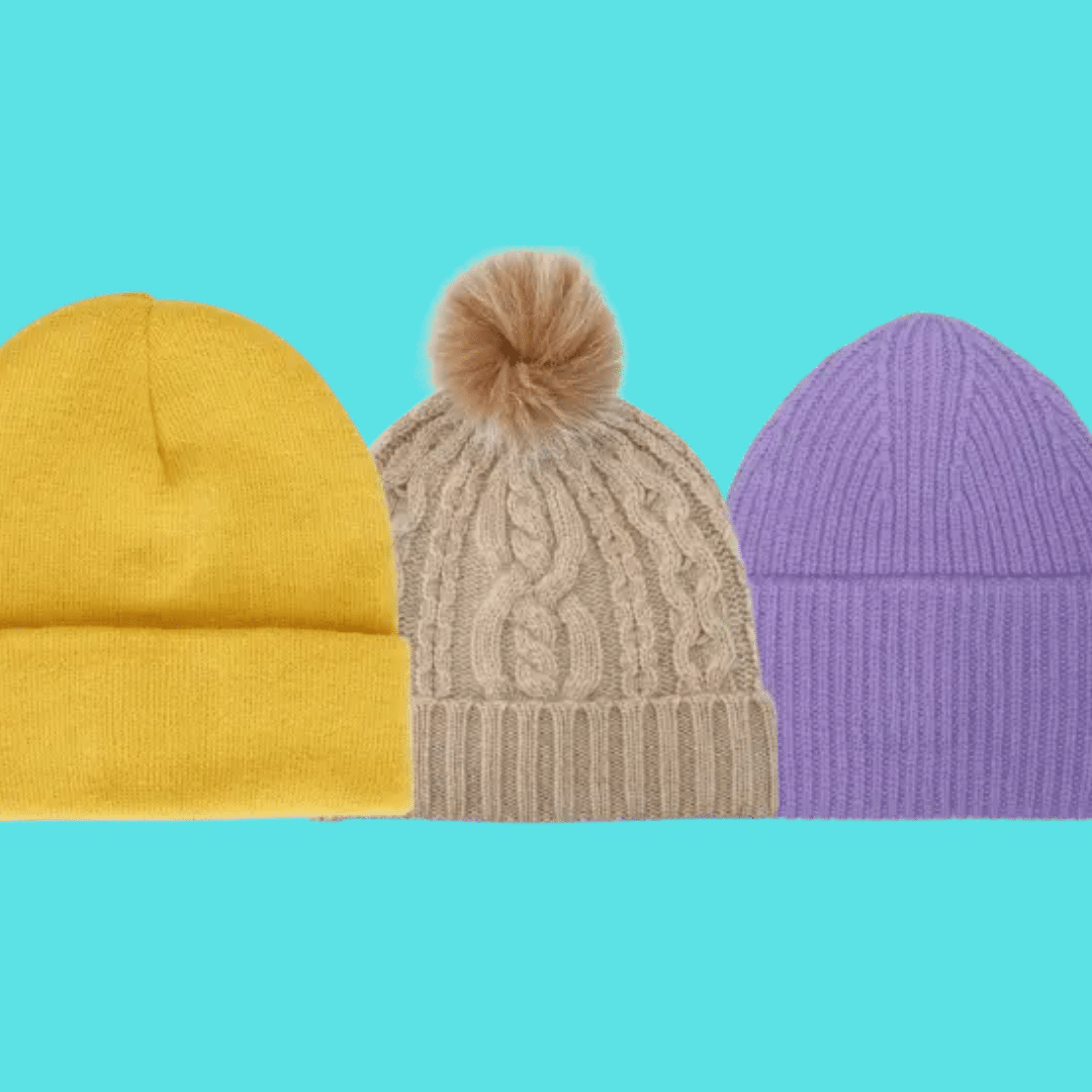 Three knit beanies in yellow, beige with a fur pom-pom, and lavender, lined up on a teal background.
