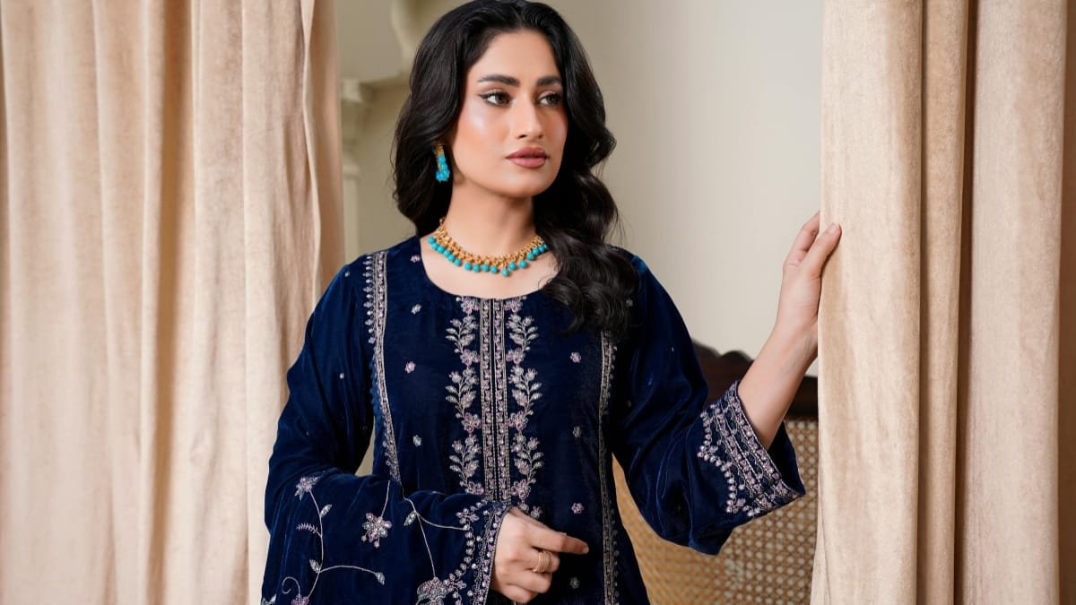 Elegant woman wearing a navy embroidered dress with matching turquoise jewelry indoors.