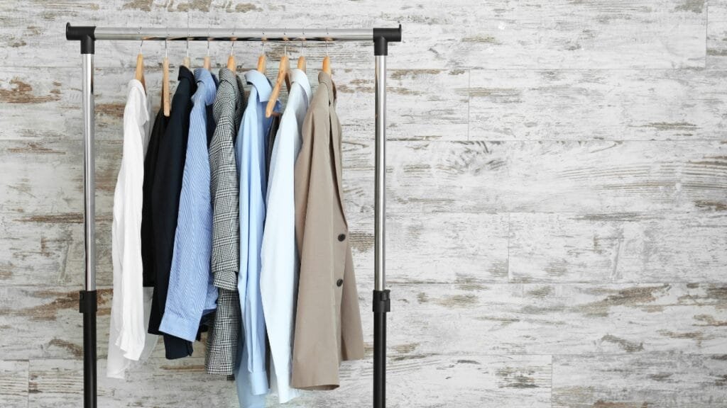A clothing rack displaying several shirts in neutral colors—white, black, gray, and beige.