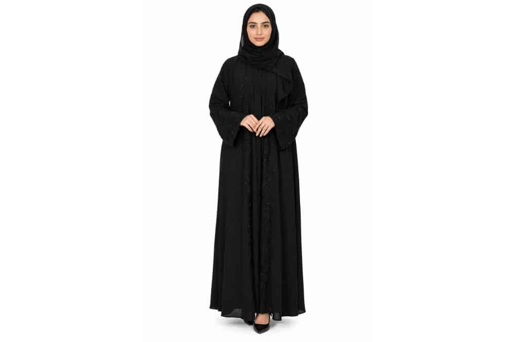 Woman wearing a black luxury abaya with a matching hijab, photographed against a white background.