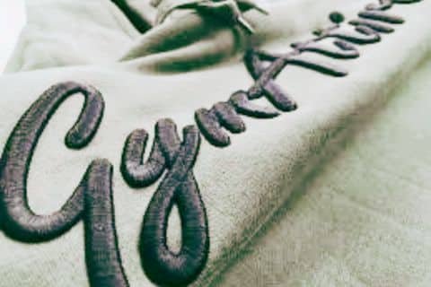 Close-up of embroidered "Gym Attire" on fabric.