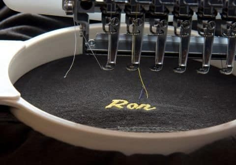 Embroidery machine stitching "Run" on black fabric.