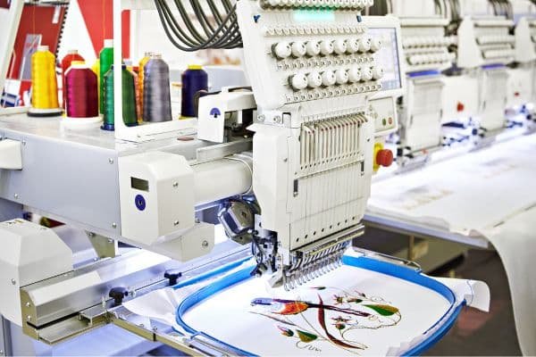 A sewing/embroidery machine stitching colorful thread on fabric.