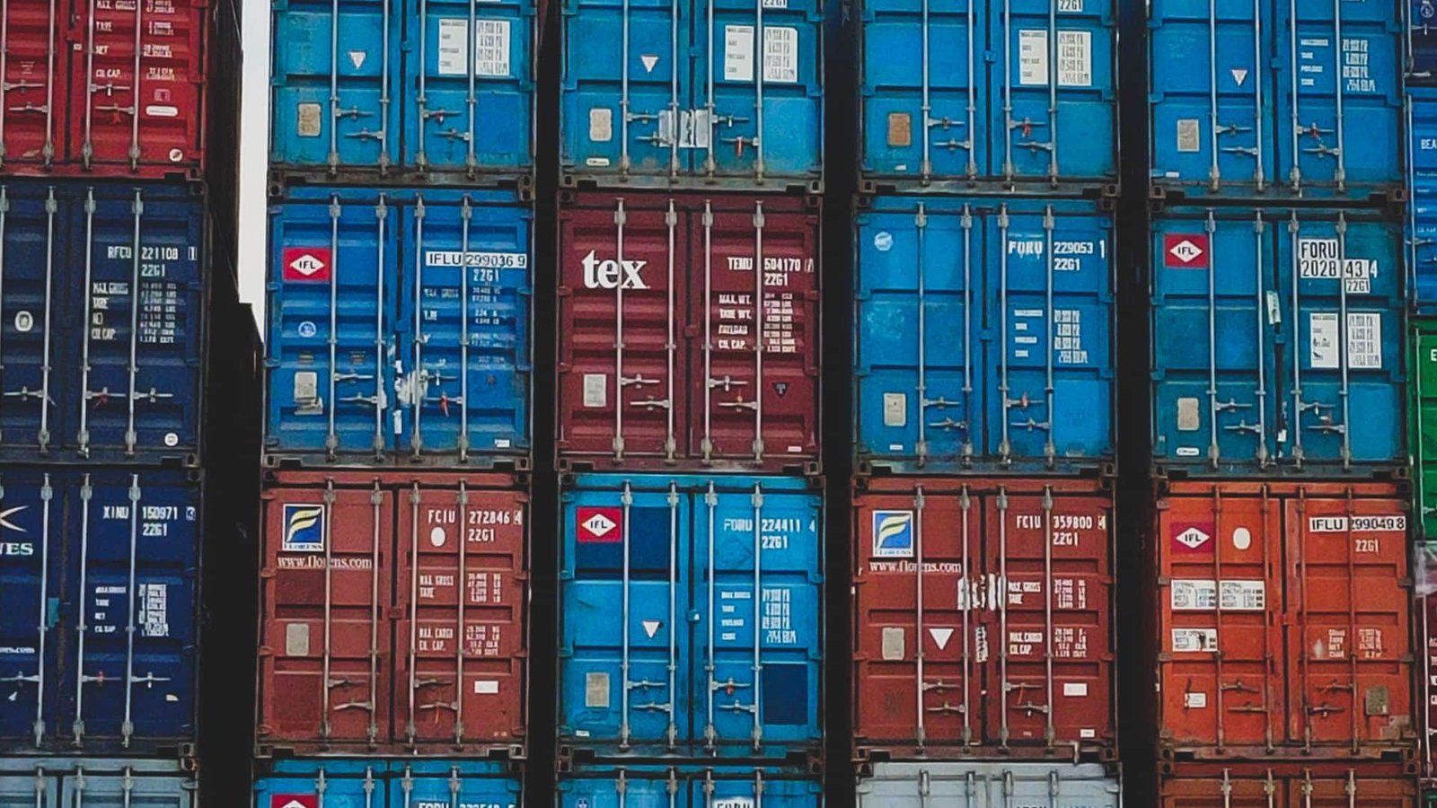 Stacked shipping containers in various colors, symbolizing global trade and logistics.