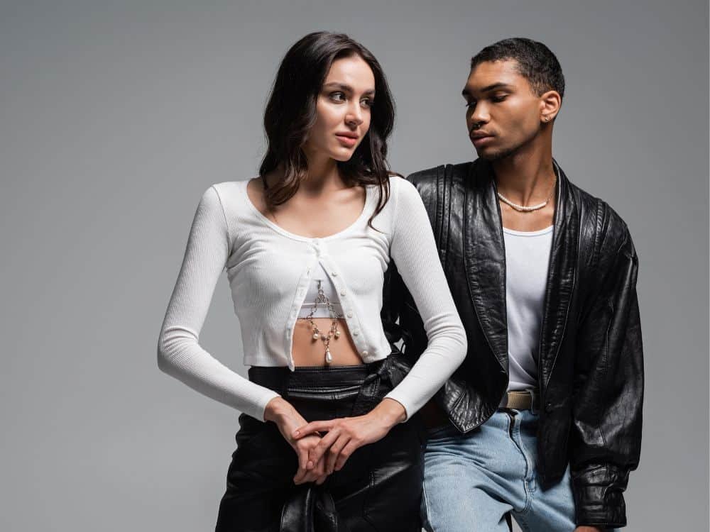 Fashionable couple posing together in trendy outfits against a neutral background.