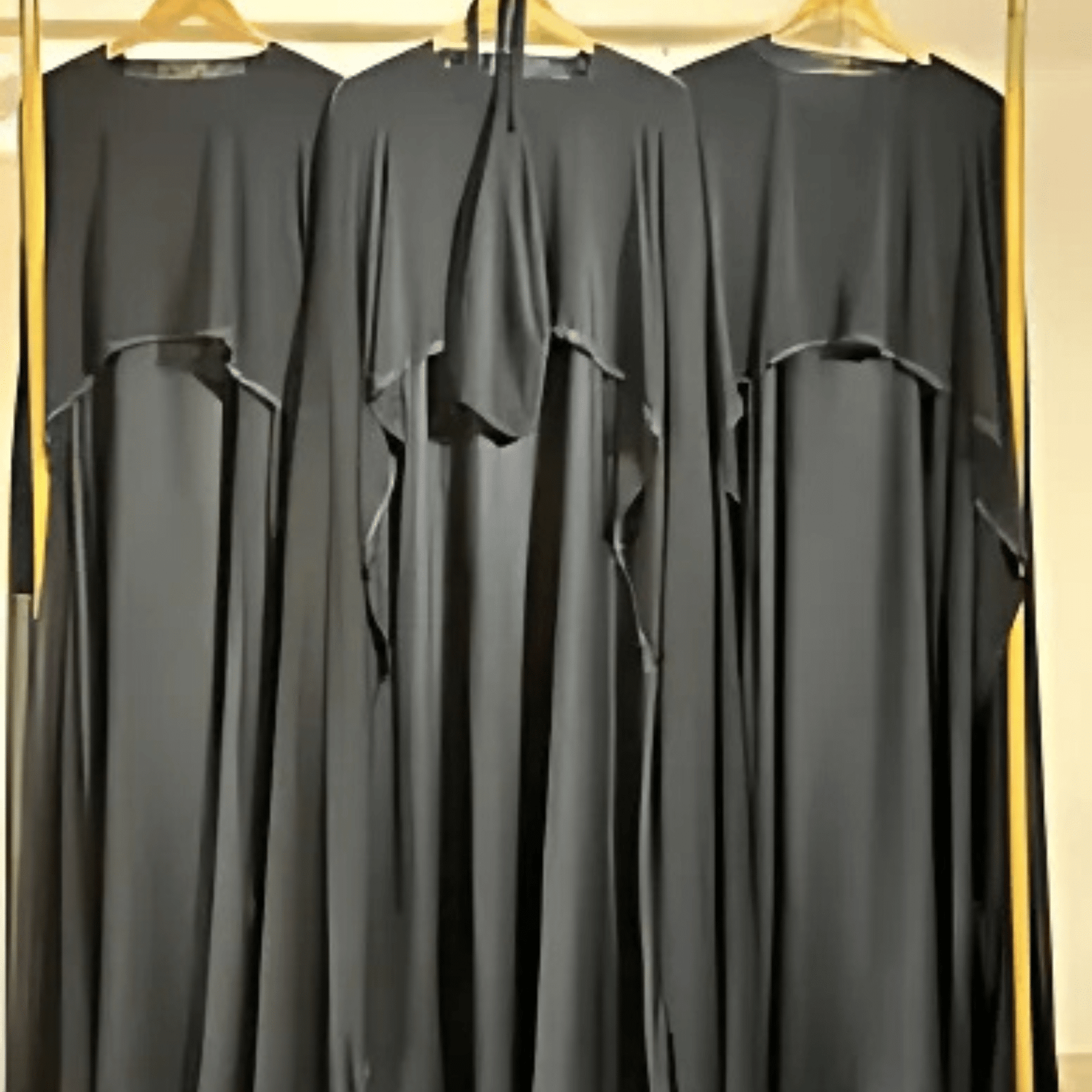 Colorful collection of wholesale abaya designs hanging on display rack.