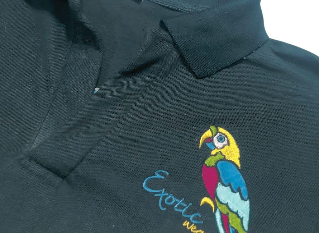 Close-up of a black polo shirt with colorful embroidered parrot design and the word "Evolve" beneath it.